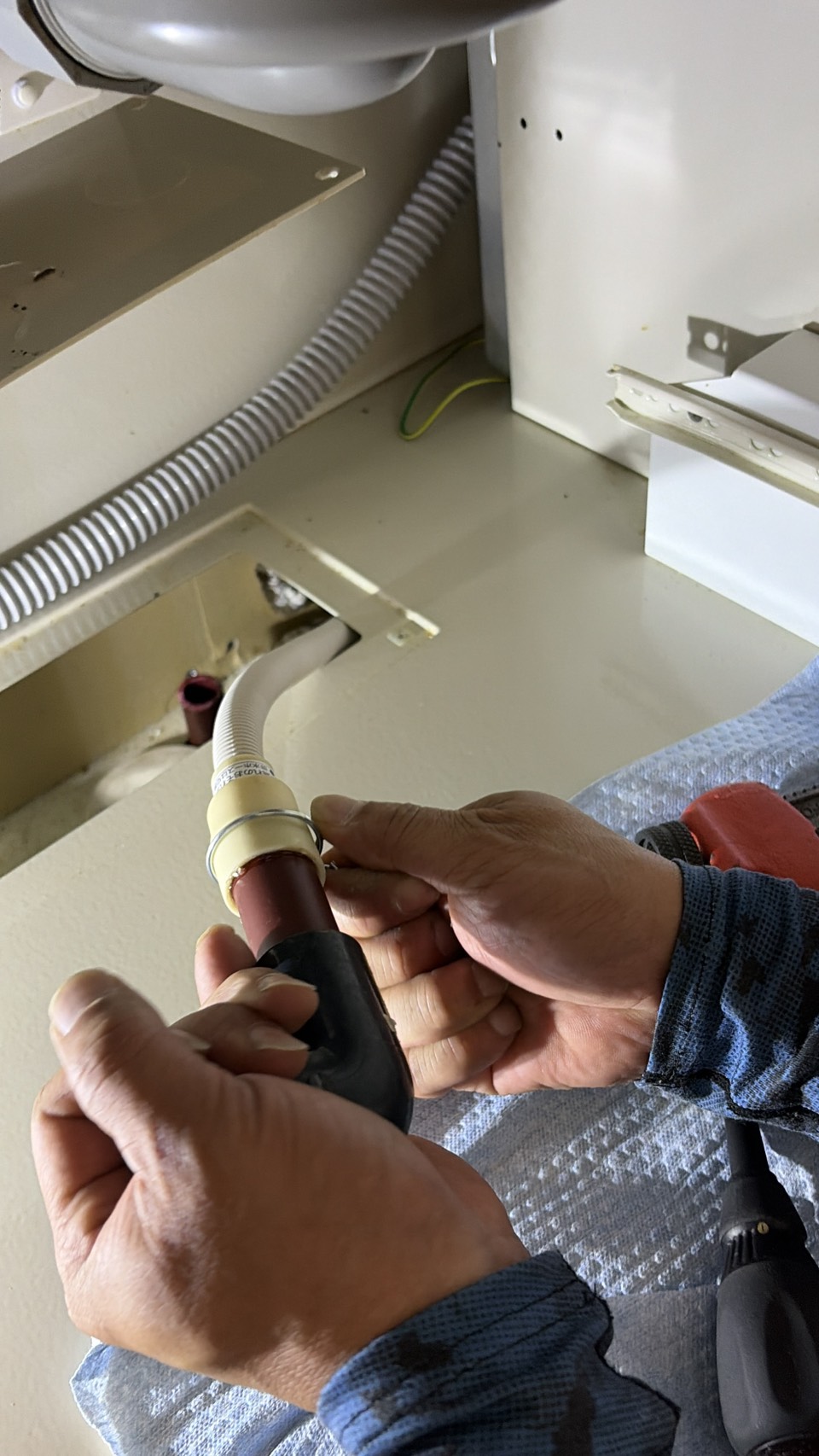 食洗機交換工事で給排水ホースを接続している様子